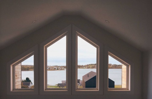 Riverport Cabin | A sanctuary of architectural restraint and unmediated coastal observation, enhanced by illuminated waters.